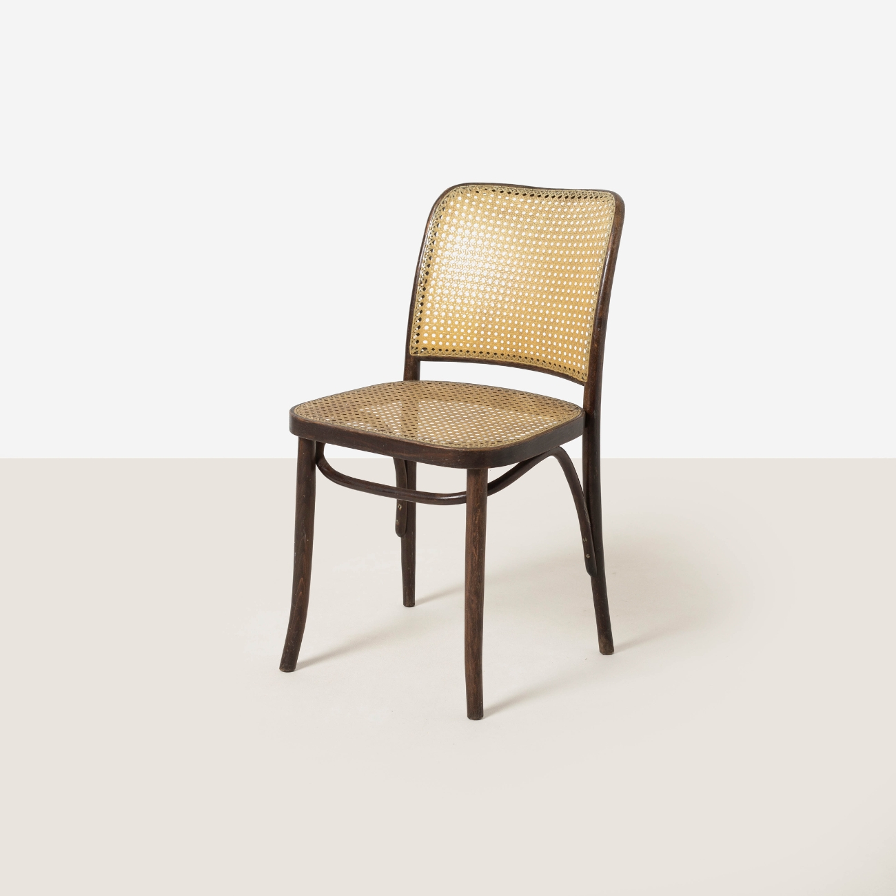 Rear three-quarter view of dark stained beech dining chair with woven backrest