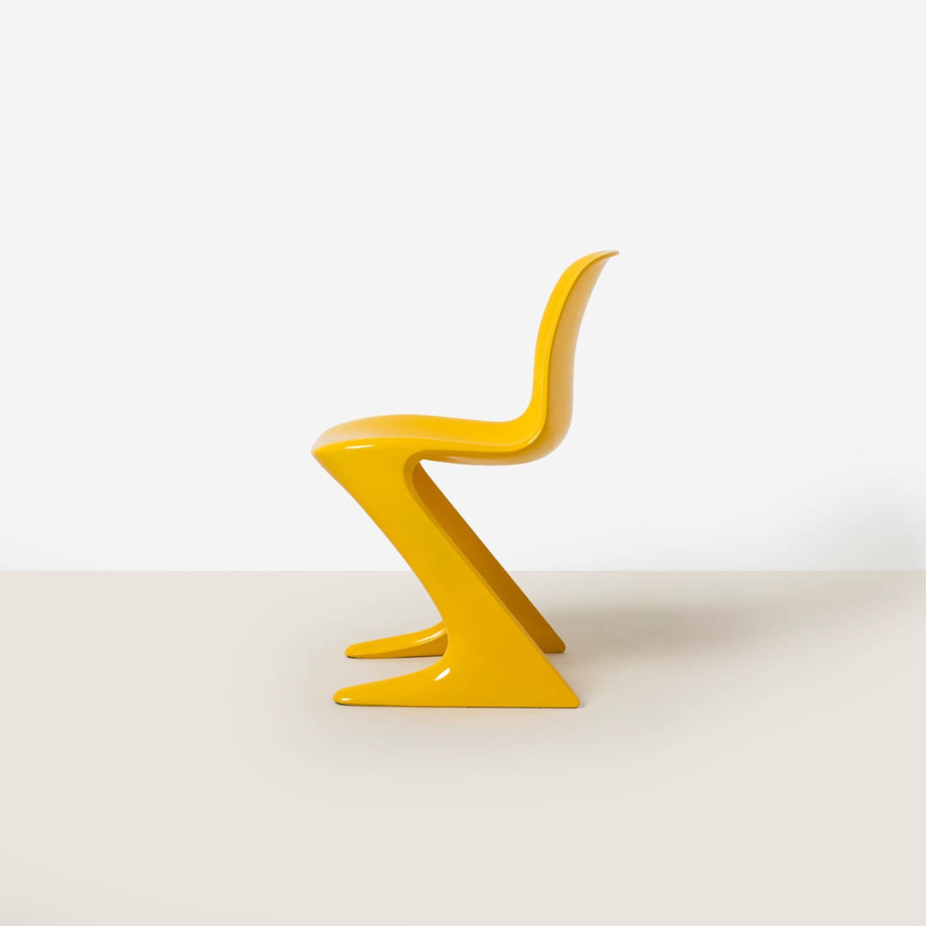 Side profile of a yellow Z-Stuhl chair showing the continuous transition from seat to structural base.