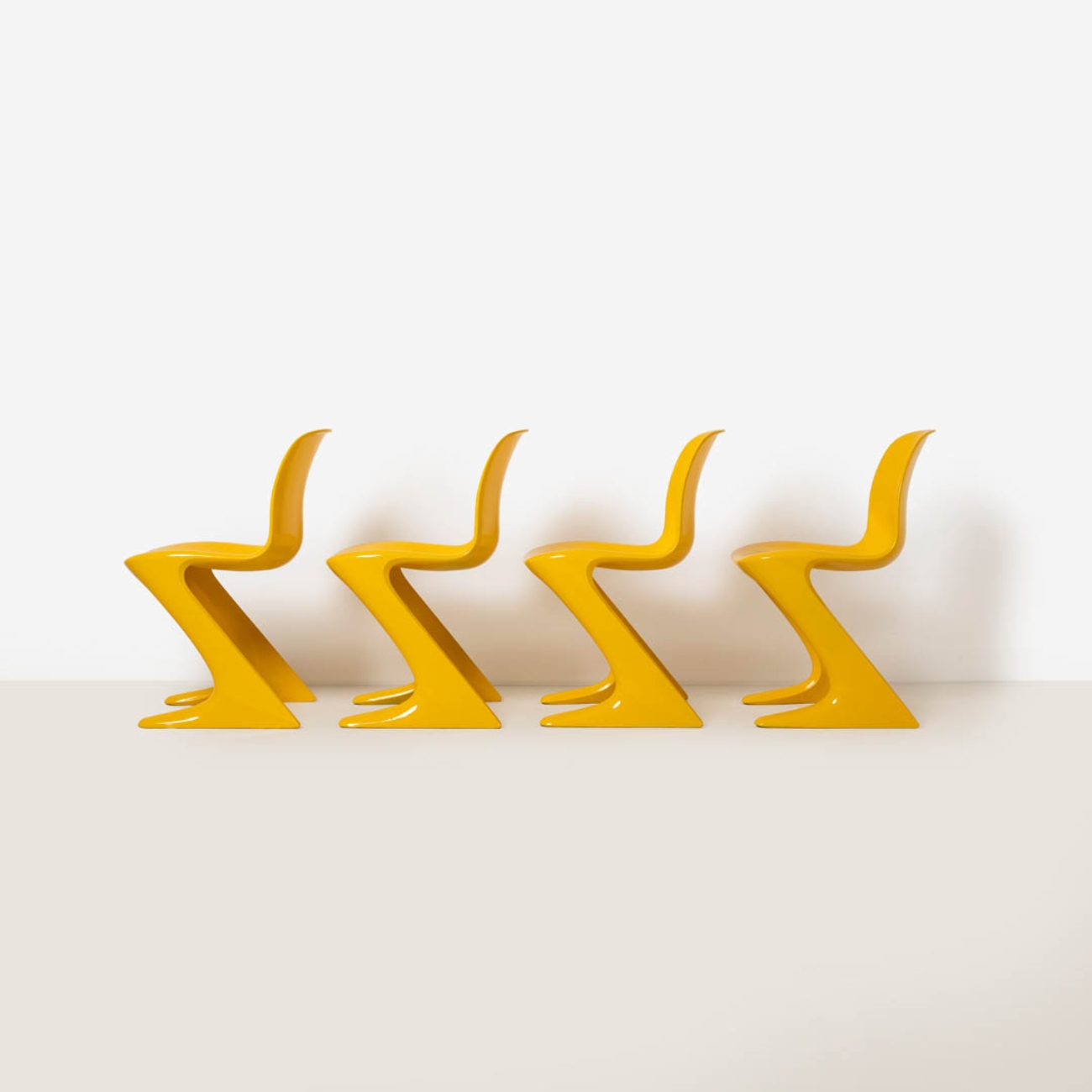 Side profile of four yellow Z-Stuhl chairs highlighting the distinctive Z-shaped structural silhouette.