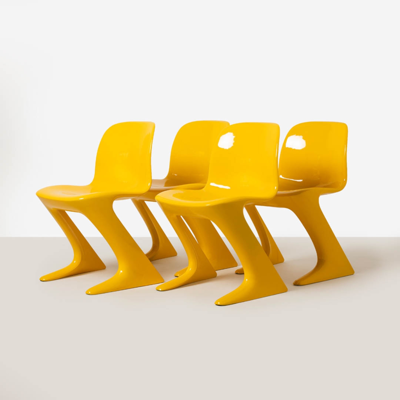 Set of four yellow Z-Stuhl chairs shown in a three-quarter view emphasizing their sculptural one-piece construction.