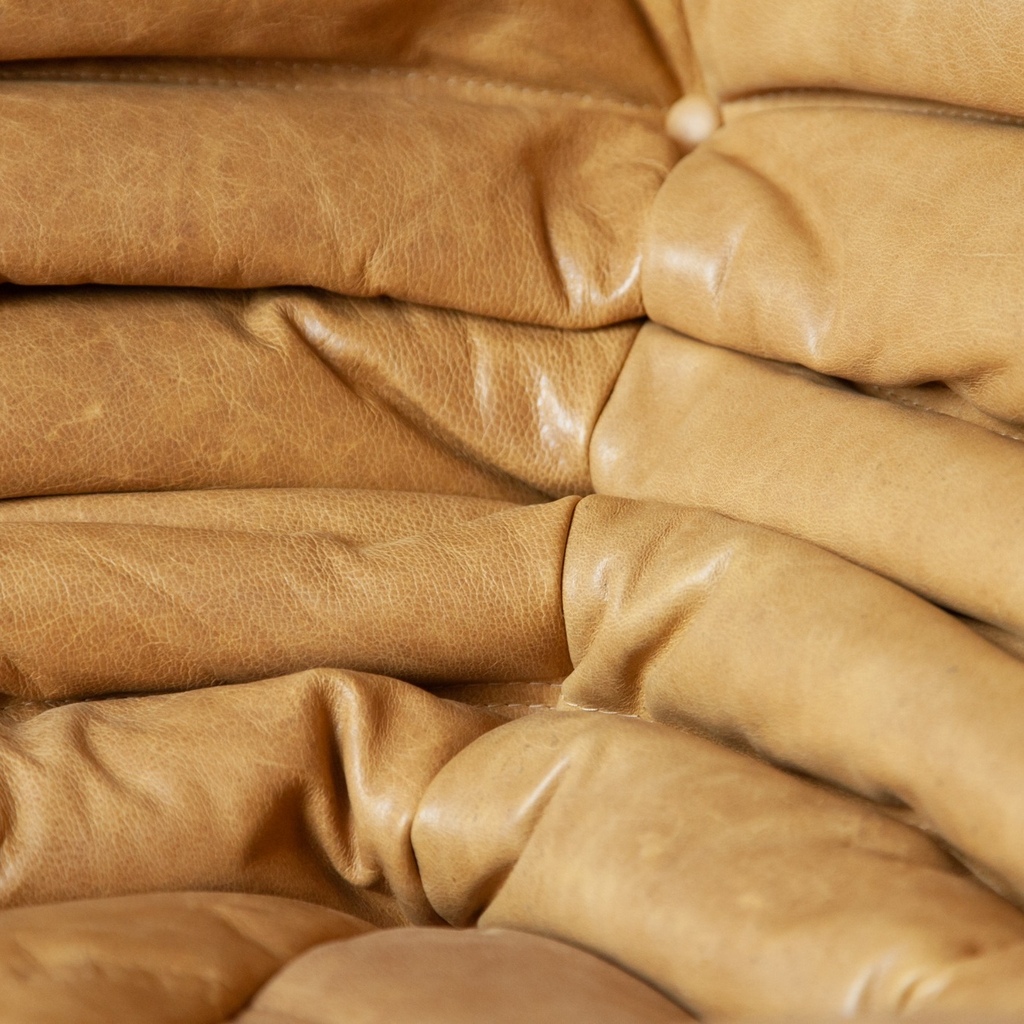 Pufa Togo vintage, detal pikowania jasnobrązowej skóry Brown Leather Camel z guzikami tapicerskimi, głębokimi marszczeniami i widocznymi przeszyciami.
