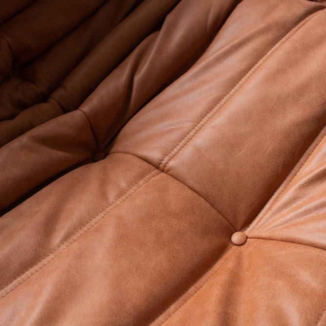 Pufa Togo vintage, zbliżenie pikowanego siedziska w skórze Brown Leather Peach, z guzikiem tapicerskim, promienistymi marszczeniami i widocznymi przeszyciami.