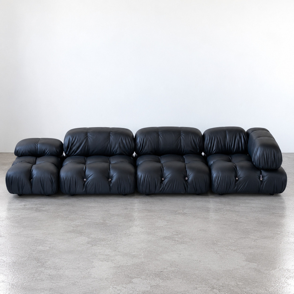 Sofa modułowa Camaleonda vintage w czarnej skórze naturalnej, widok od frontu na długą konfigurację złożoną z kilku pikowanych modułów, proj. Mario Bellini, B&B Italia.